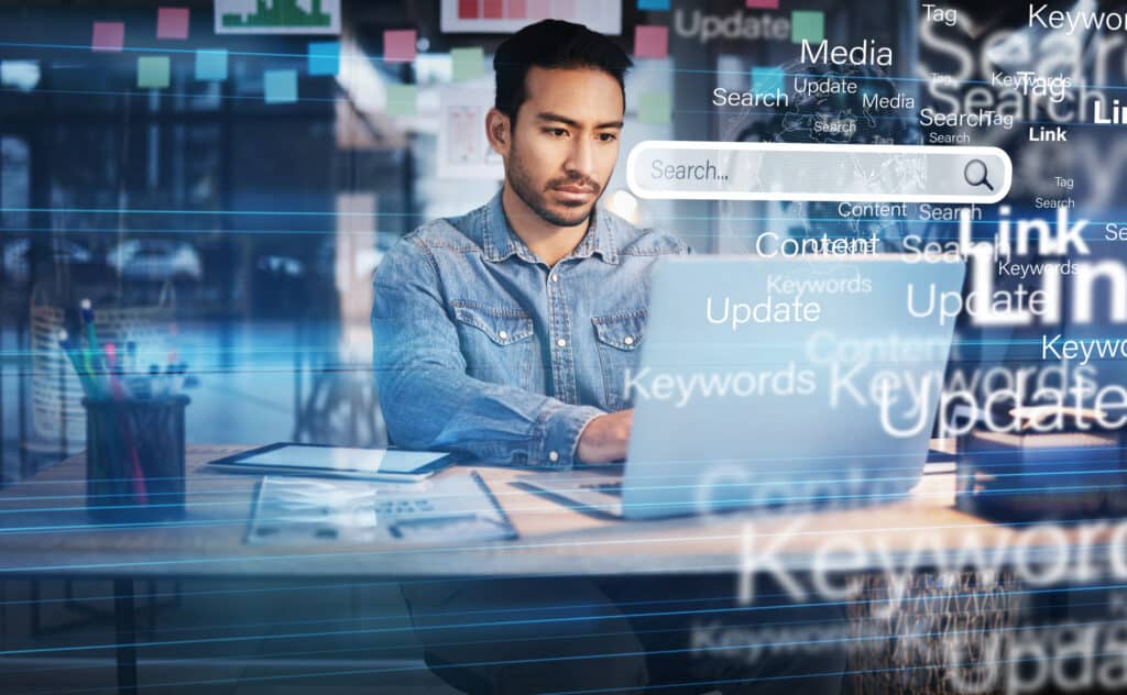 Man working on a laptop with floating search and keywords graphics representing SEO and digital marketing